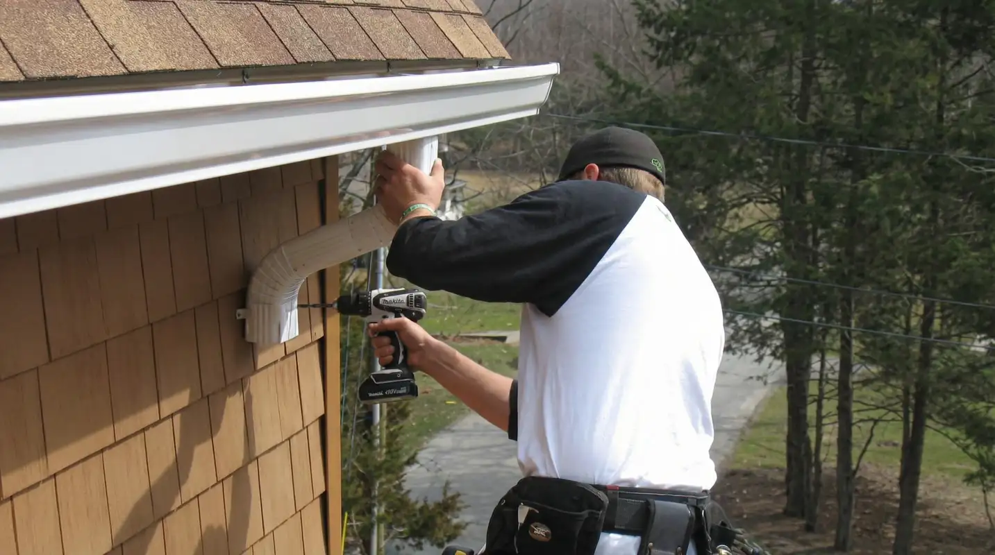 Professional contractor installing tan vinyl siding panels on a residential home exterior in Kansas City, MO
